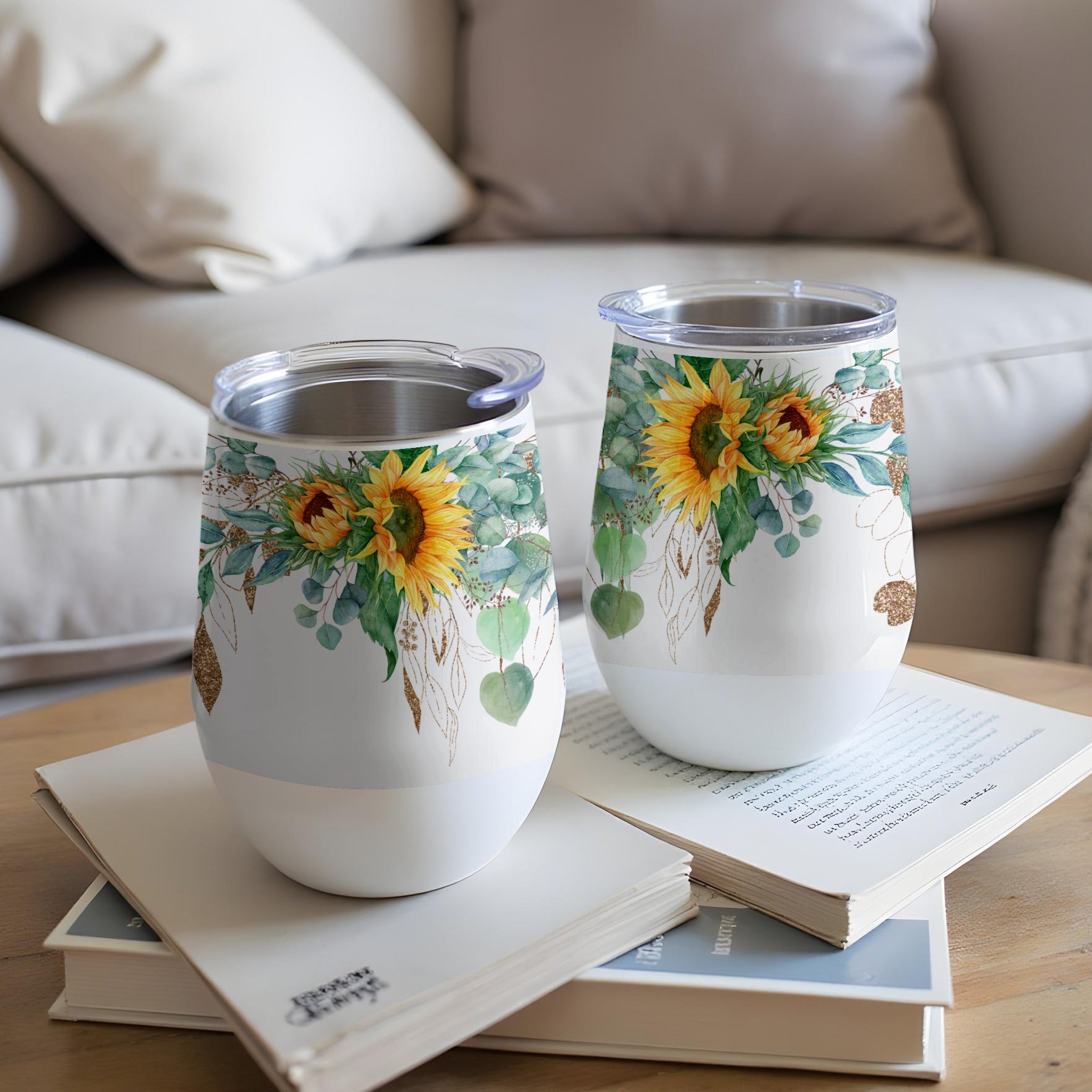 Two white tumblers with sunflowers and eucalyptus on a coffee table.