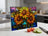 Three stained-glass sunflowers on a cutting board with tomatoes and cucumber.