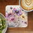 Floral design on coaster with text "Challenge YOURSELF" next to kiwi and coffee.