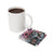 White mug with coffee beside a coaster featuring a woman and sunflowers.