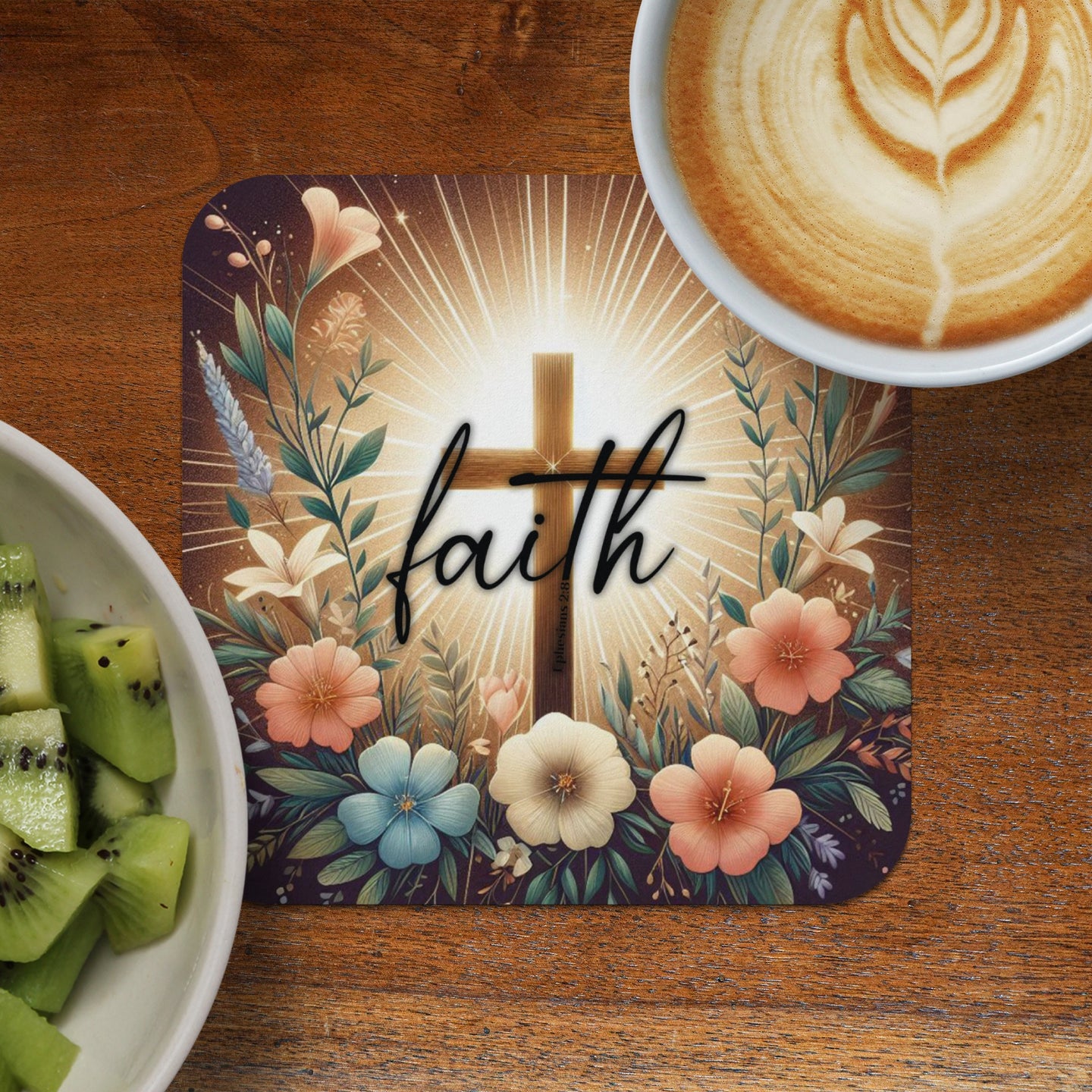 Cross with "faith" text surrounded by flowers, next to kiwi and coffee.