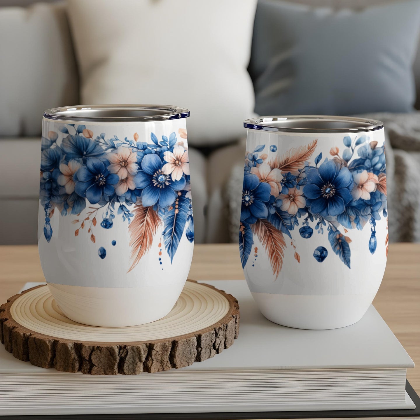 Two white wine tumblers with blue floral and feather design.