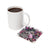 Coaster with tattooed woman in VR headset and butterflies, next to coffee mug.