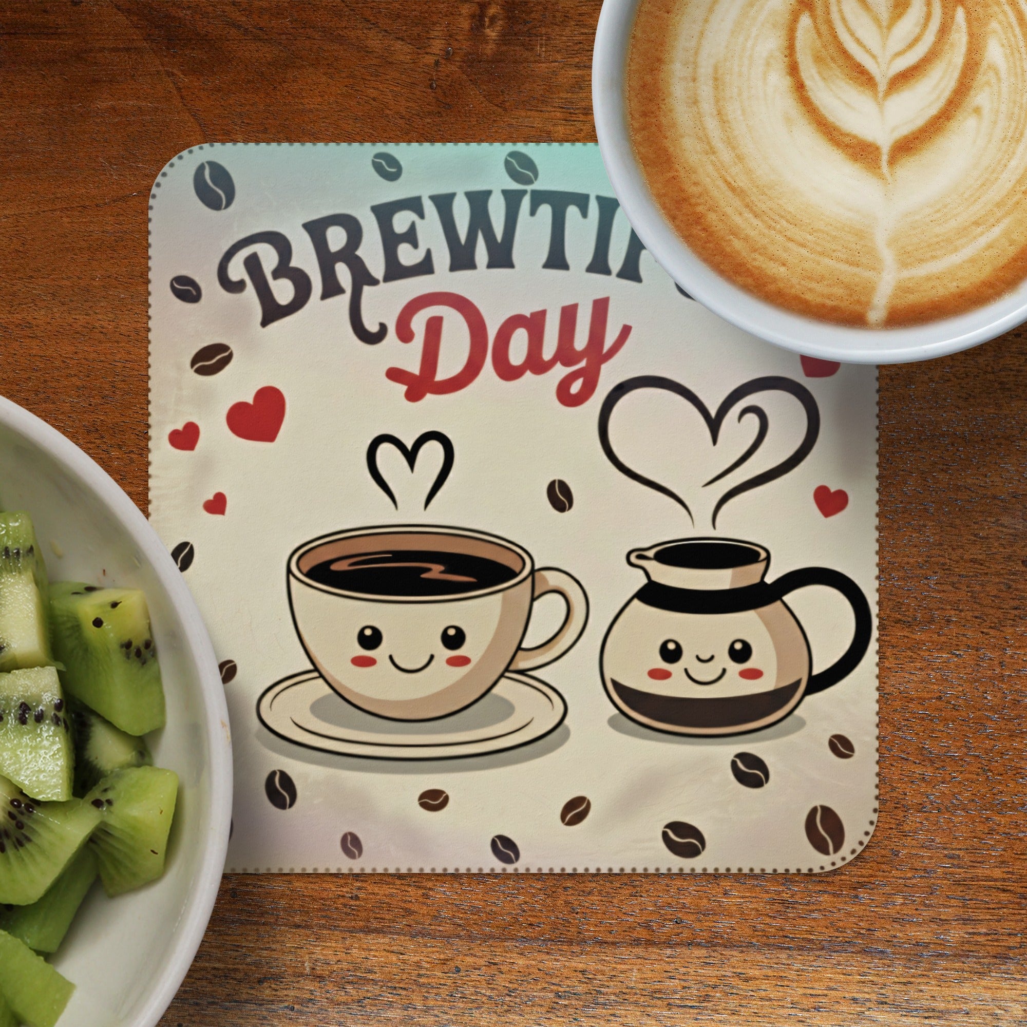 Brewing Day coaster with coffee cups, hearts, and coffee beans, next to kiwi.