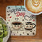 Brewing Day coaster with coffee cups, hearts, and coffee beans, next to kiwi.