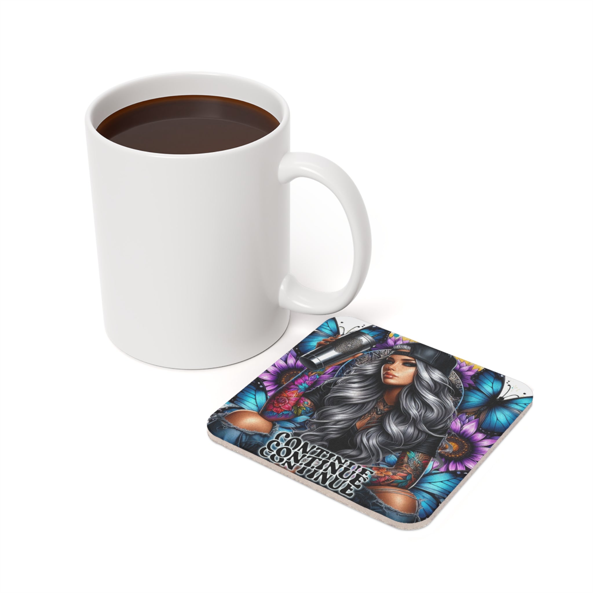 White mug of coffee next to a square coaster with a woman and butterflies.