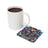 White mug of coffee next to a square coaster with a woman and butterflies.