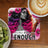 Woman with colorful hair on "I am ENOUGH" coaster, with coffee and kiwi.