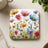 Square coaster with colorful wildflowers and foliage illustration.