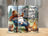 Gnome in cowboy hat sits by campfire with beer bottles and RV.