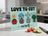 Cutting board with cartoon tomato, onion, and broccoli, and text "LOVE TO CUT OURSELF".