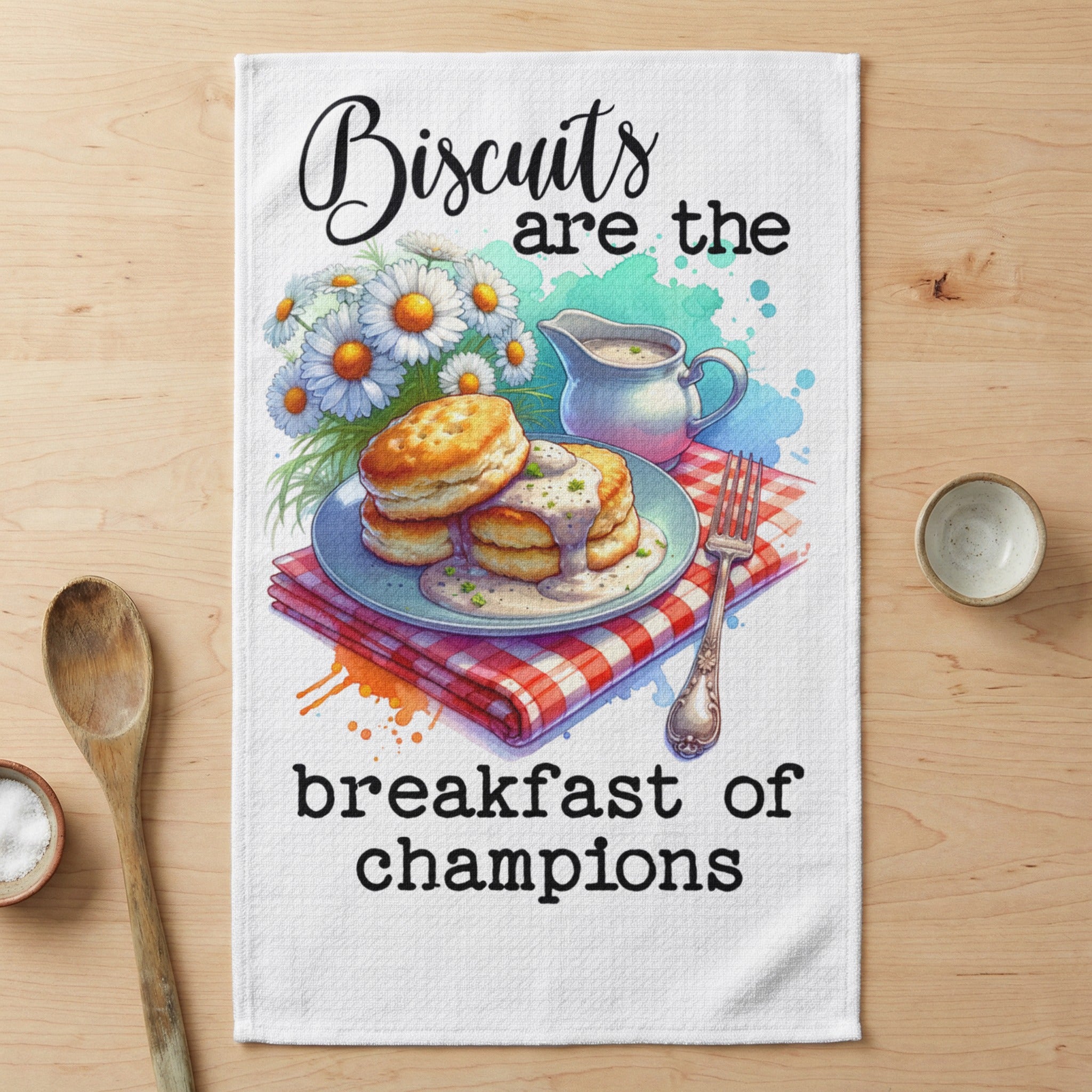 Biscuits are the breakfast of champions text on a tea towel with stacked biscuits and daisies.