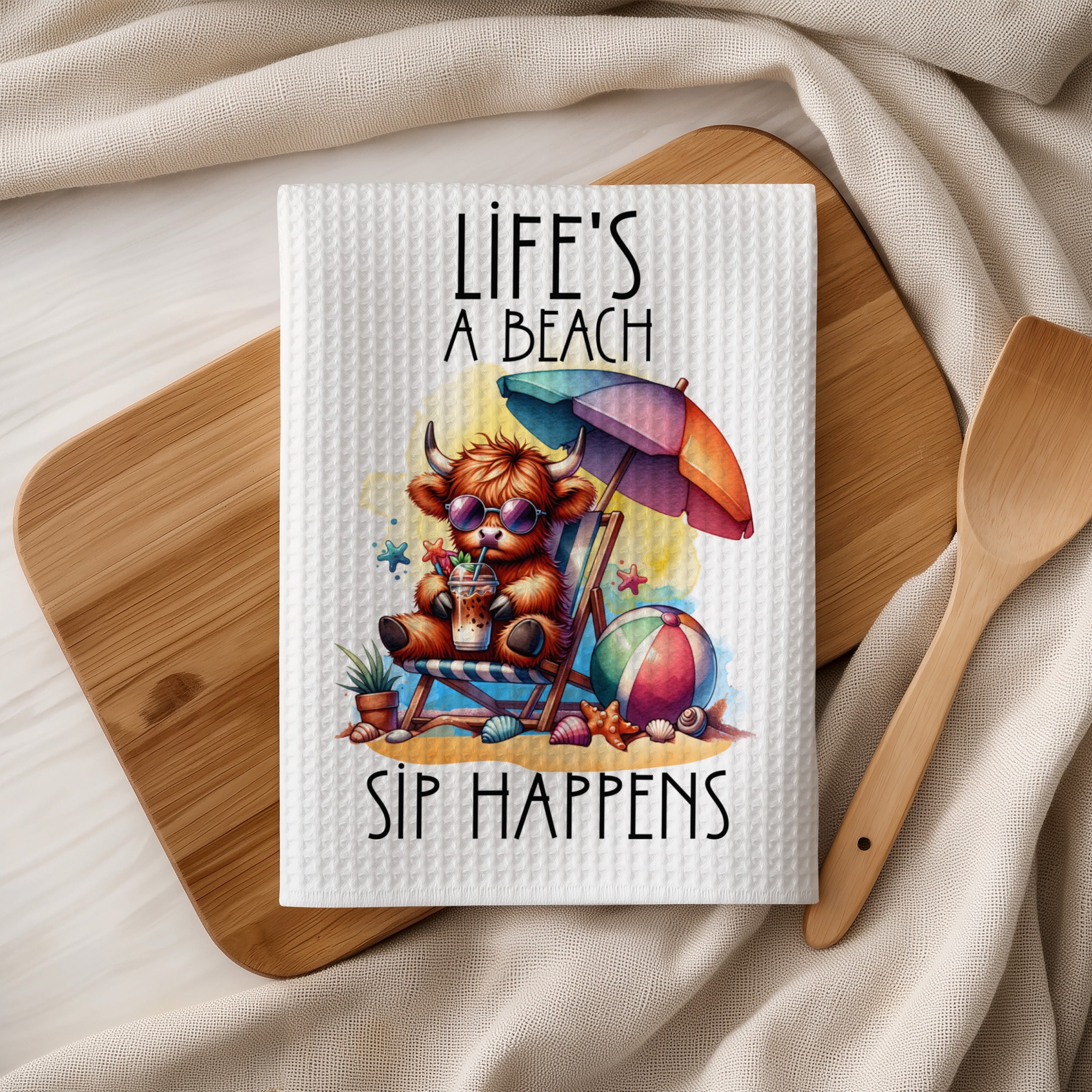 Highland cow on beach with umbrella and drink, text "Life's A Beach Sip Happens".