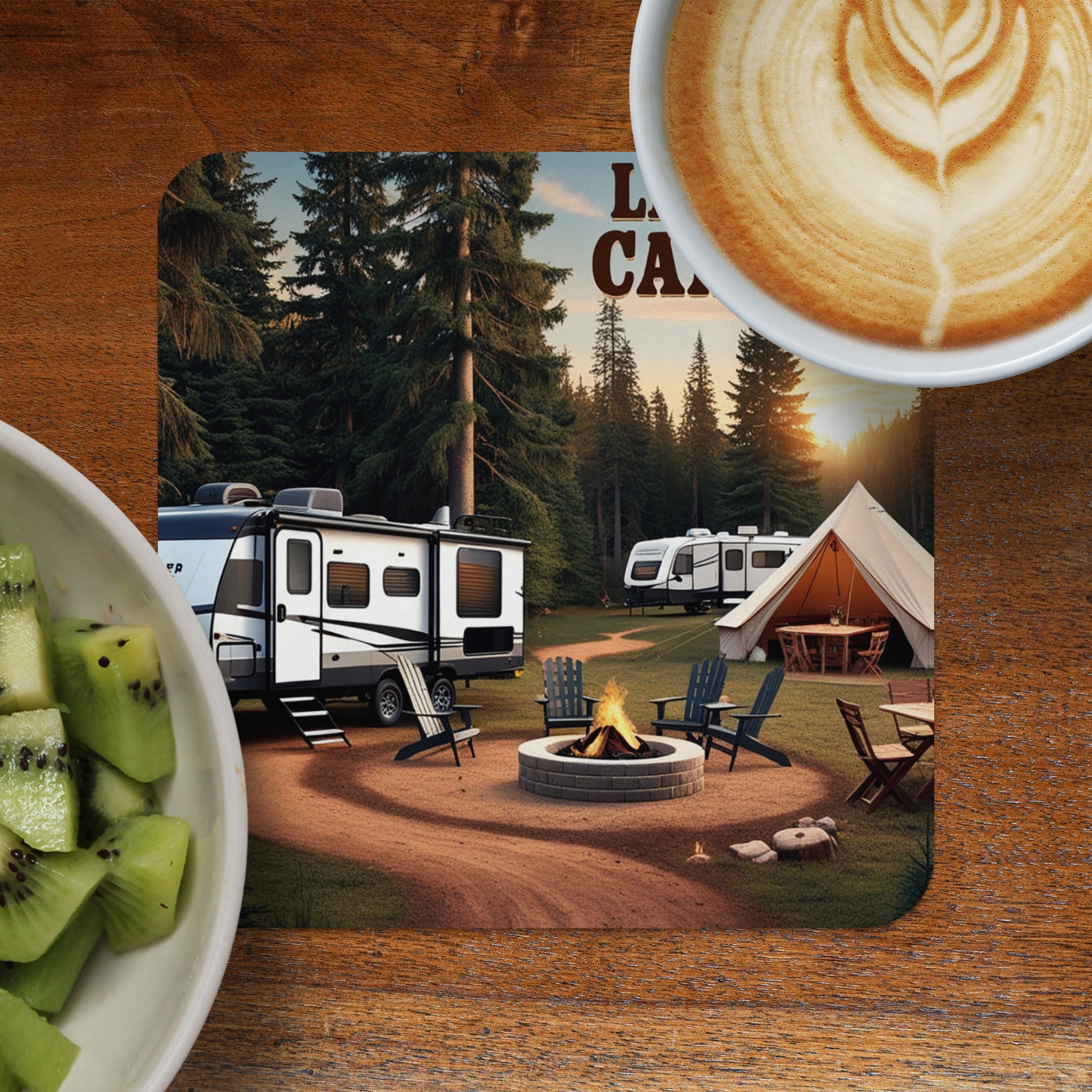 Camper trailer, tent, and fire pit in a wooded campsite with coffee.