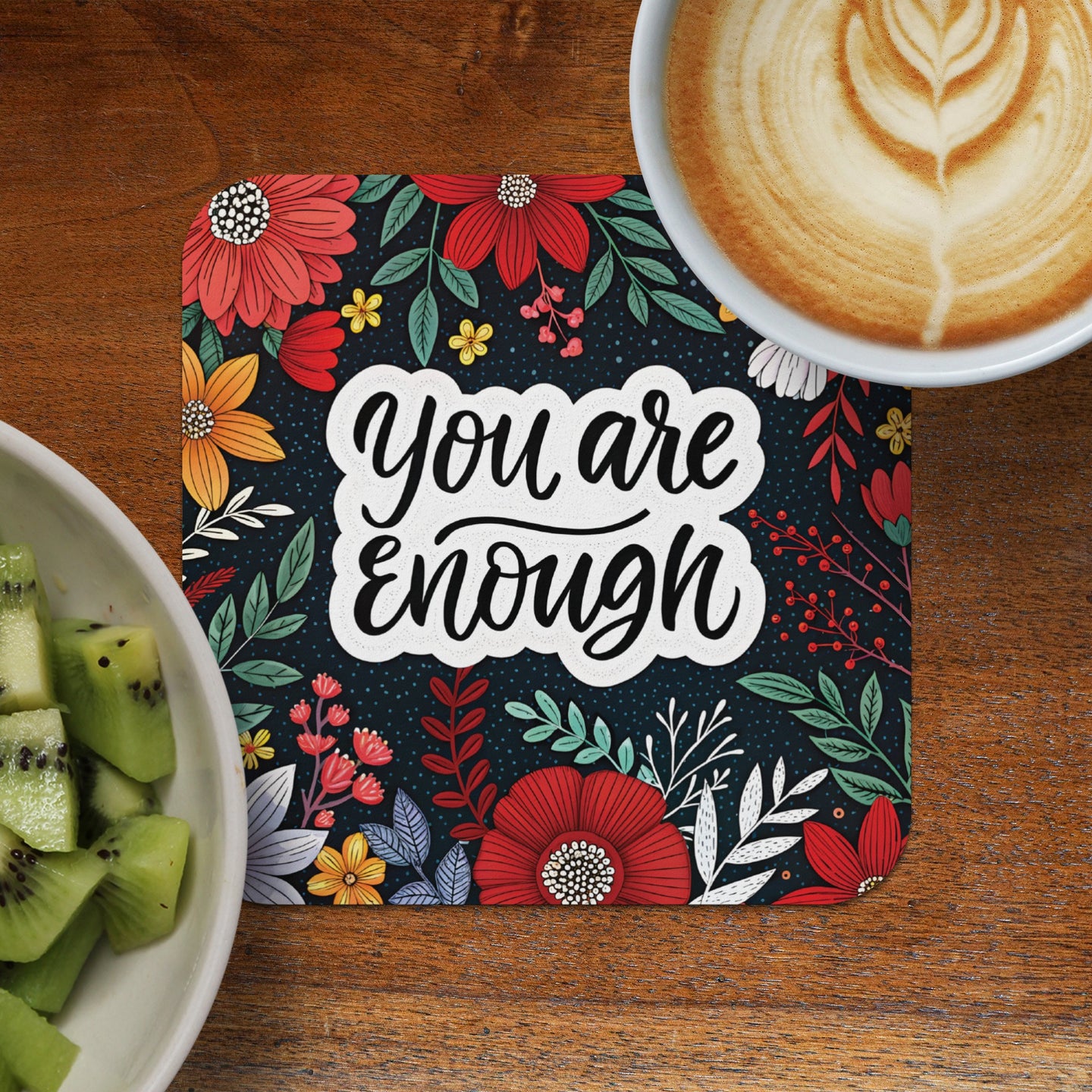 Coaster with "You are enough" text and floral design, next to kiwi slices and coffee.