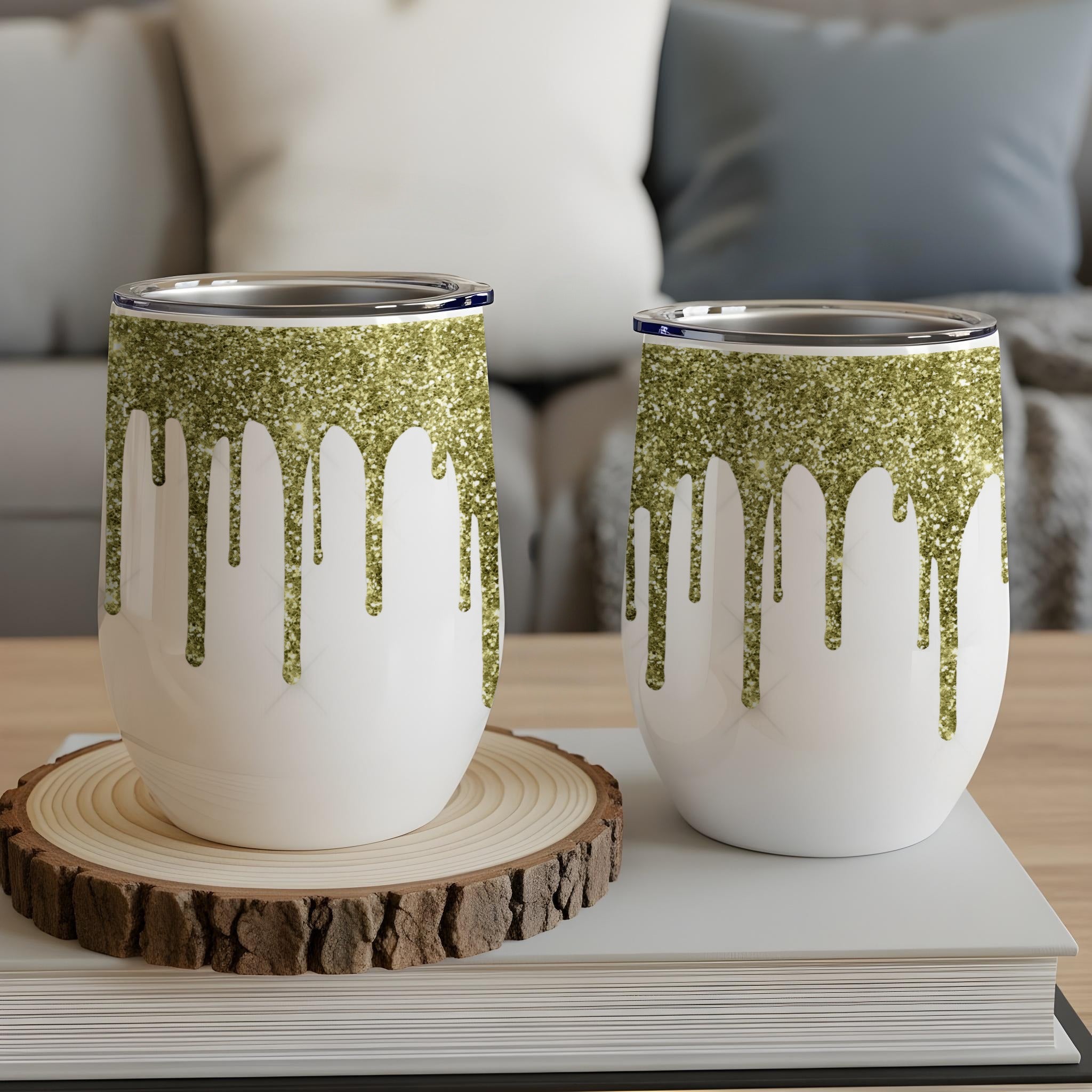 Two white glitter-dripped stemless wine tumblers on a wood slice.