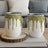 Two white glitter-dripped stemless wine tumblers on a wood slice.