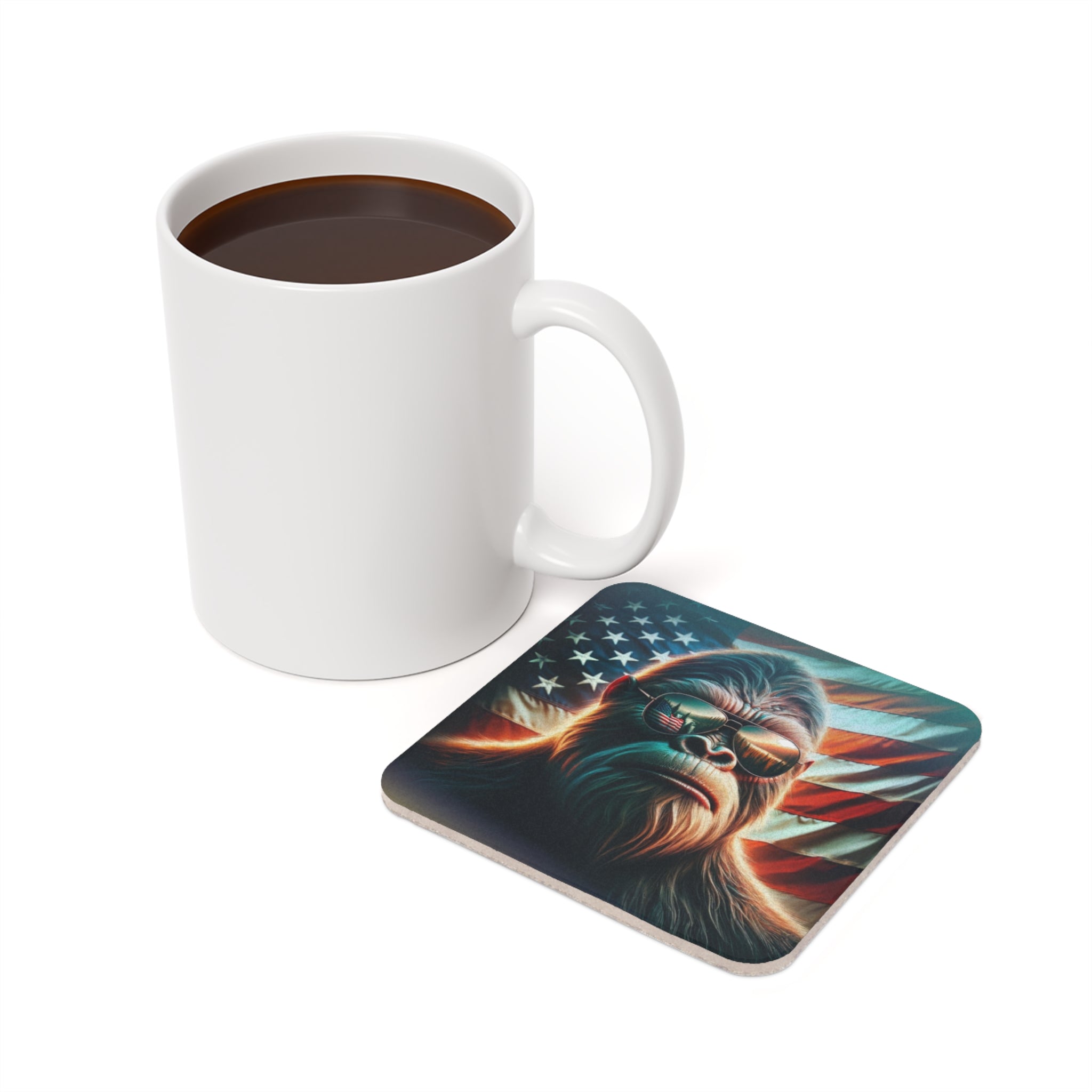 Gorilla in sunglasses with American flag on a coaster next to coffee mug.
