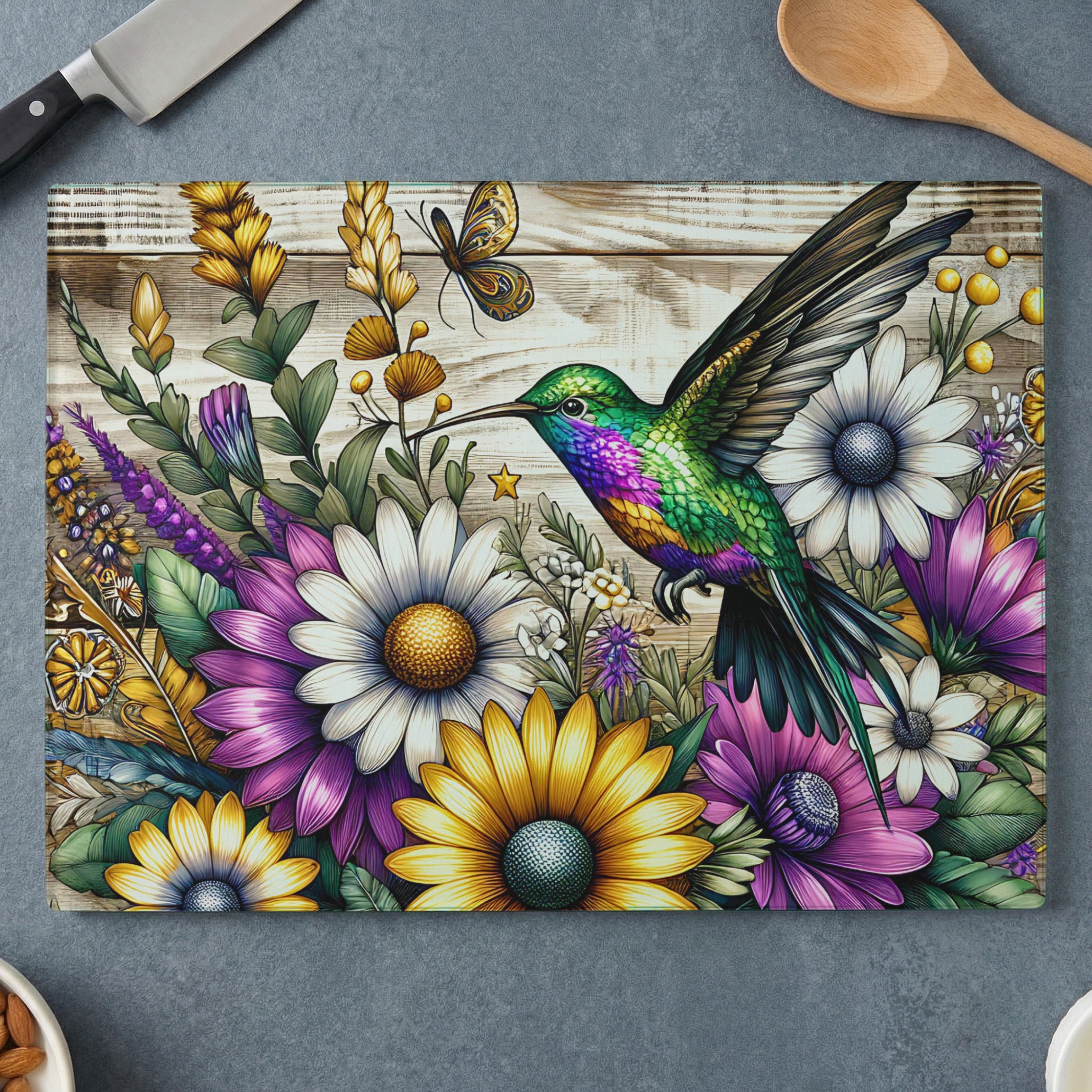 Hummingbird and flowers on a wooden cutting board with kitchen utensils.