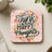 Coaster with "Think Happy Thoughts" in script over pink stripes with floral accents.