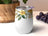 White tumbler with yellow and green floral design and purple lid.