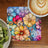Colorful watercolor floral coaster next to kiwi and coffee.