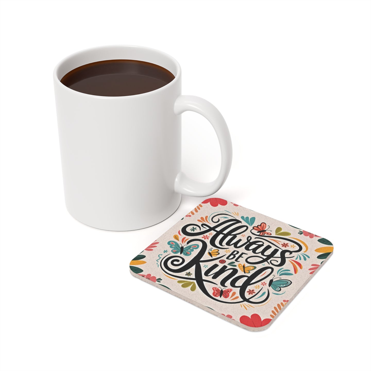 White mug of coffee next to a colorful coaster with "Always Be Kind" text.