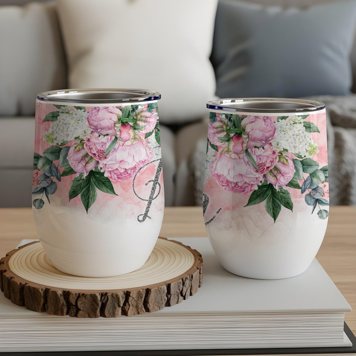 Two wine tumblers with floral designs and glitter initial 'L' and 'J'.