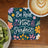 Coaster with "Be Real Not Perfect" text and floral design next to kiwi and coffee.