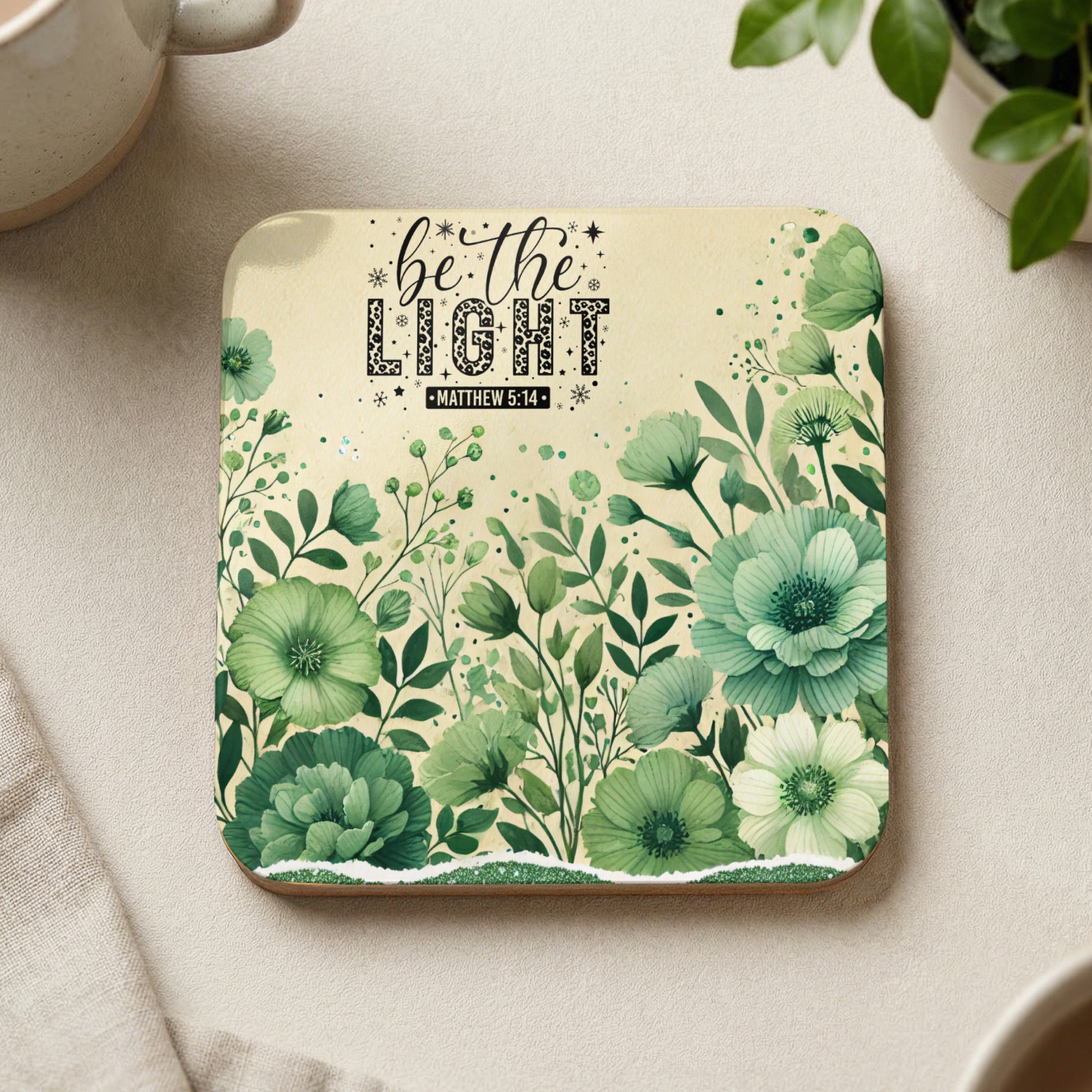 Coaster with "be the LIGHT" text and green floral watercolor design.
