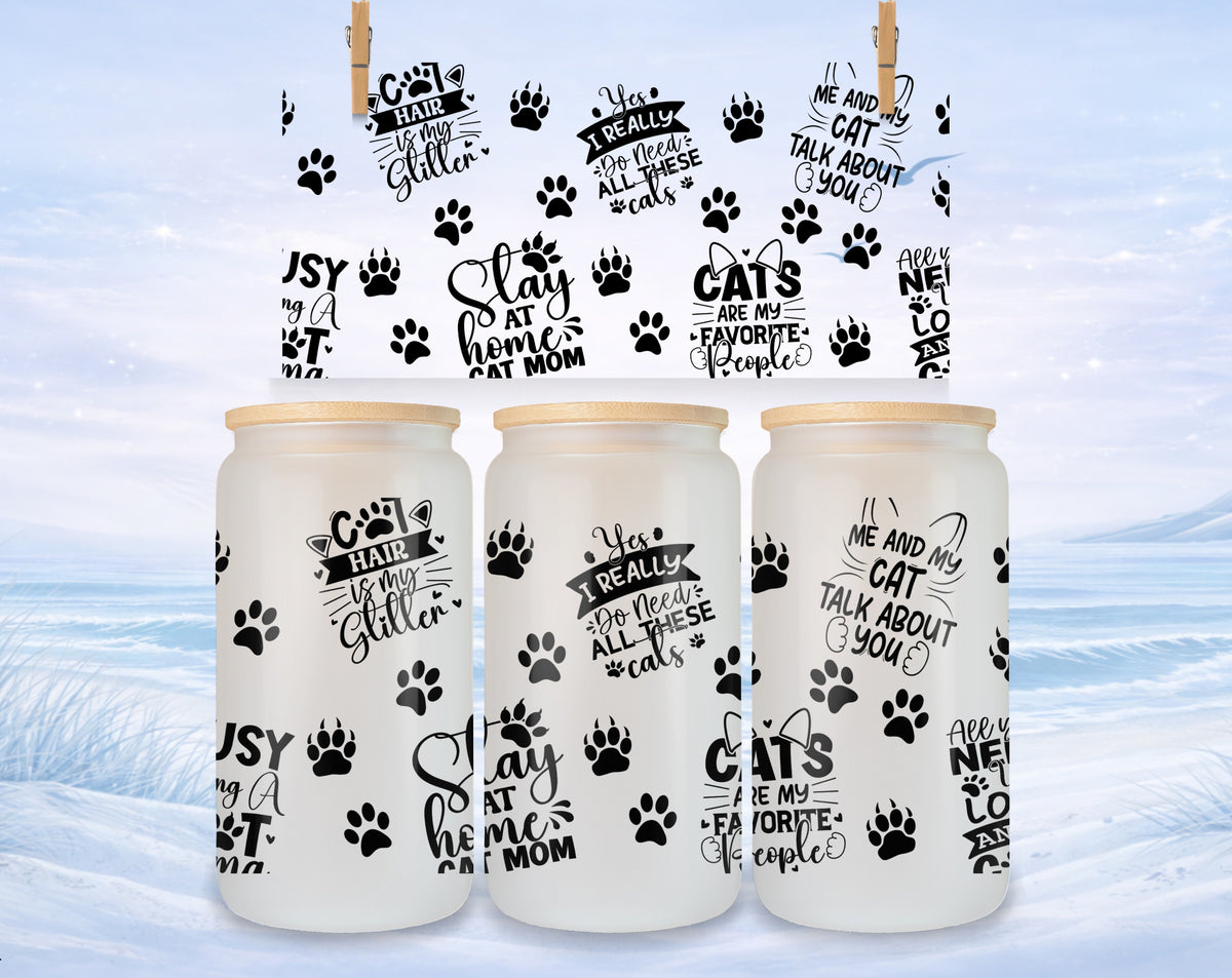 Three glass tumblers with cat-themed text and designs on a snowy background.