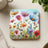 Colorful wildflower illustration with poppies and assorted blooms on a square coaster.