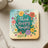 Square coaster with "Think Happy Thoughts" surrounded by colorful flowers and leaves.