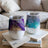 Two tumblers with swirling purple and blue glitter designs sit on open books.