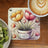 Coaster with tulips in a pot and "Embrace Life" text, next to kiwi slices and coffee.