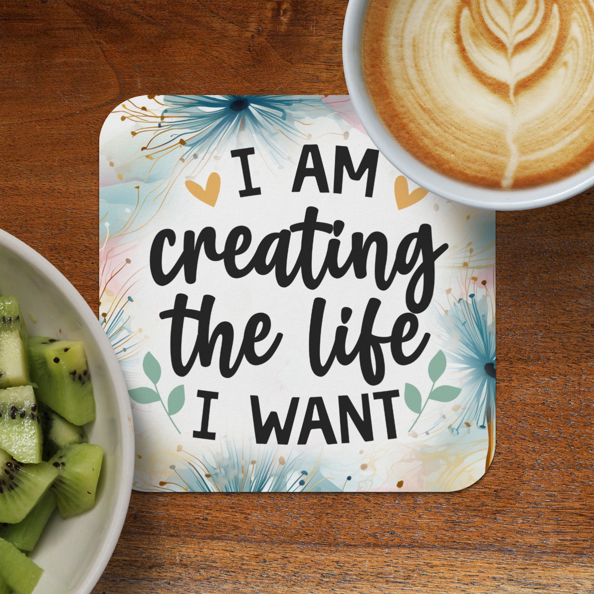 Coaster with "I AM creating the life I WANT" text, next to kiwi and coffee.