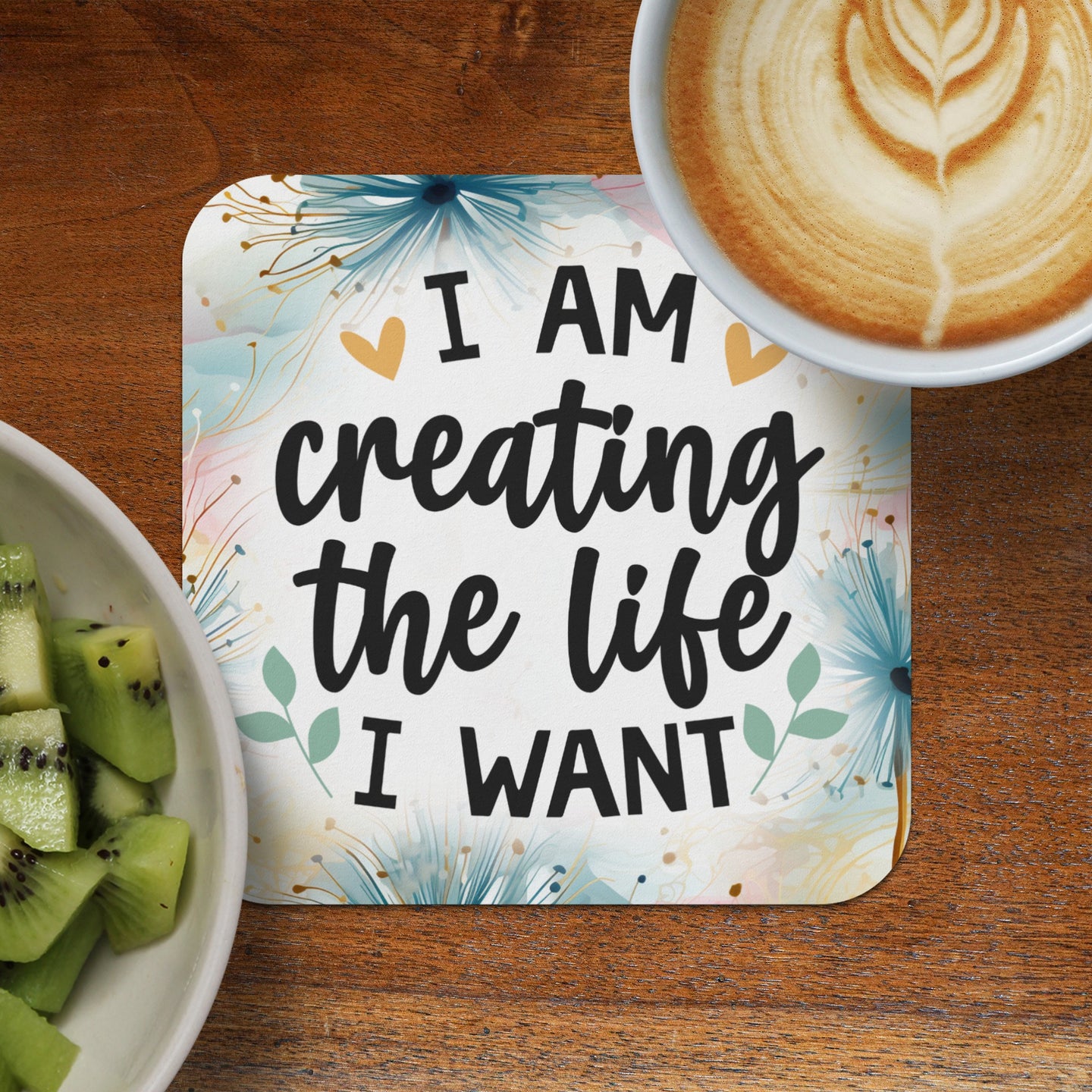 Coaster with "I AM creating the life I WANT" text, next to kiwi and coffee.