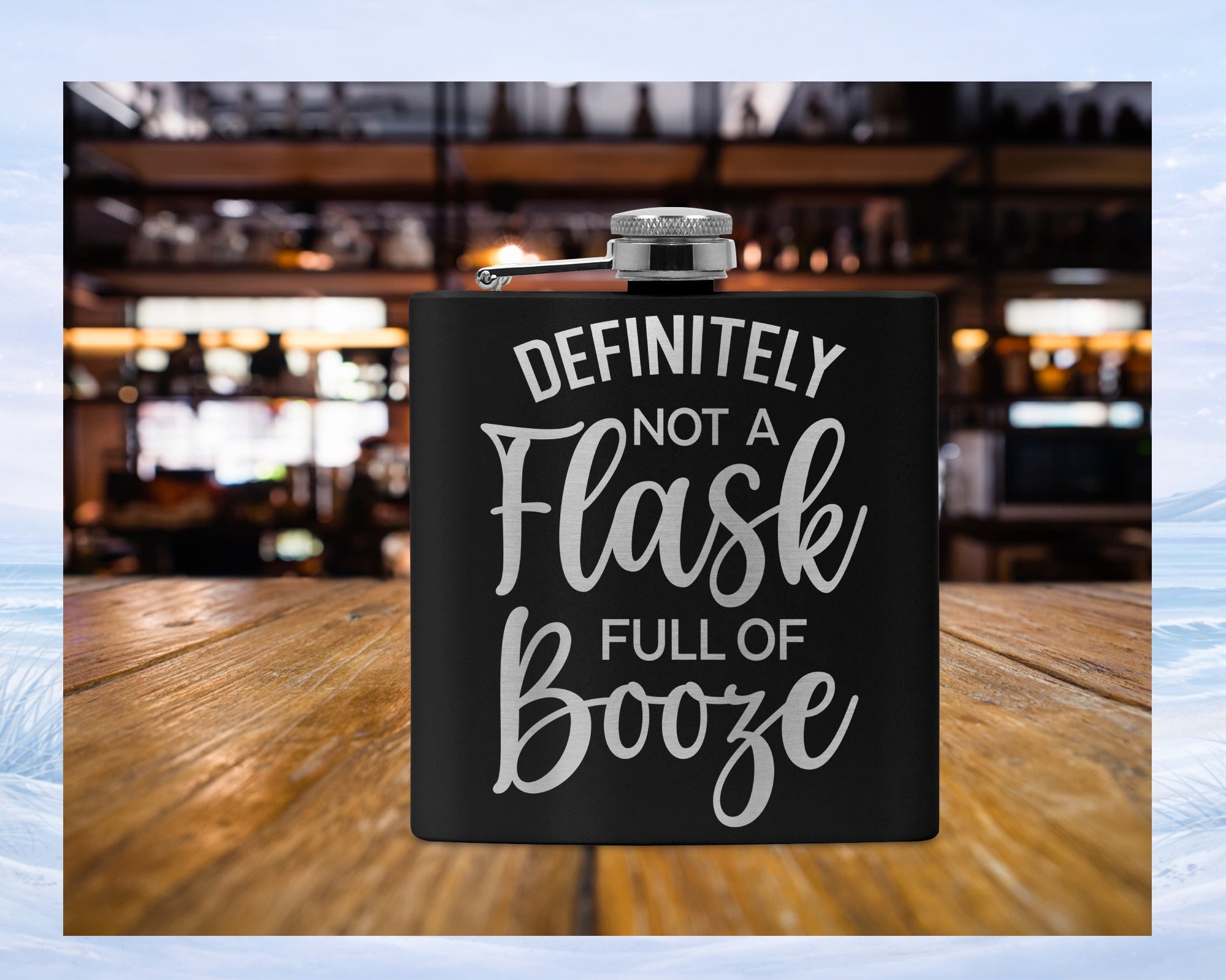 Black flask with "DEFINITELY NOT A FULL OF Booze" text, on a wooden table.