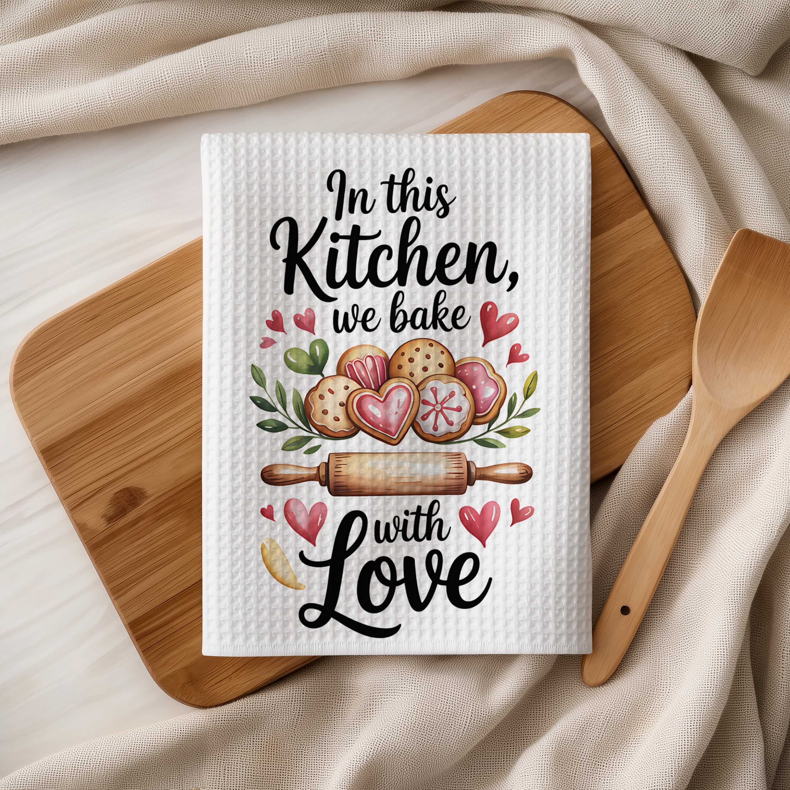 Kitchen towel with "In this Kitchen, we bake with Love" and heart-shaped cookies.