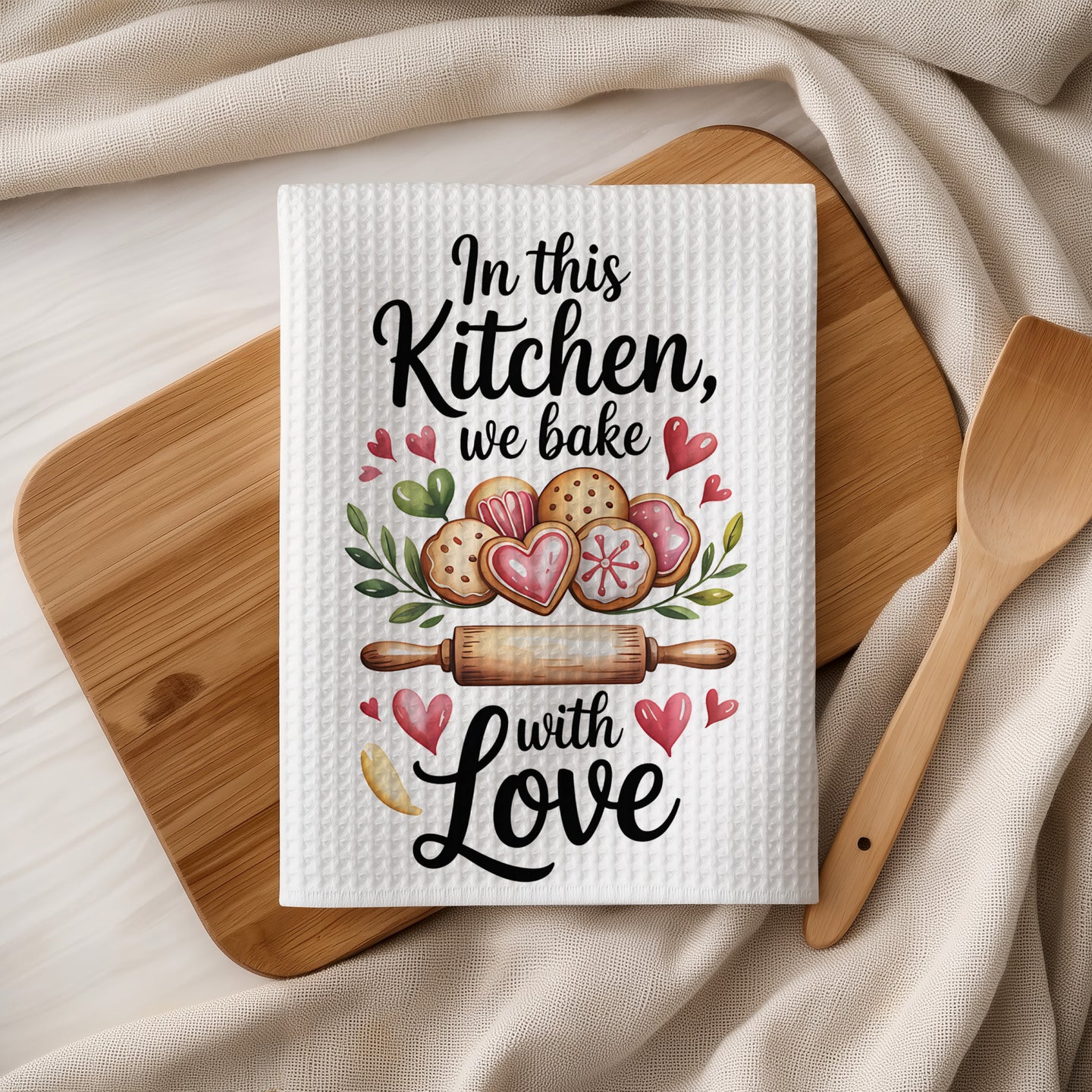 Kitchen towel with "In this Kitchen, we bake with Love" and heart-shaped cookies.