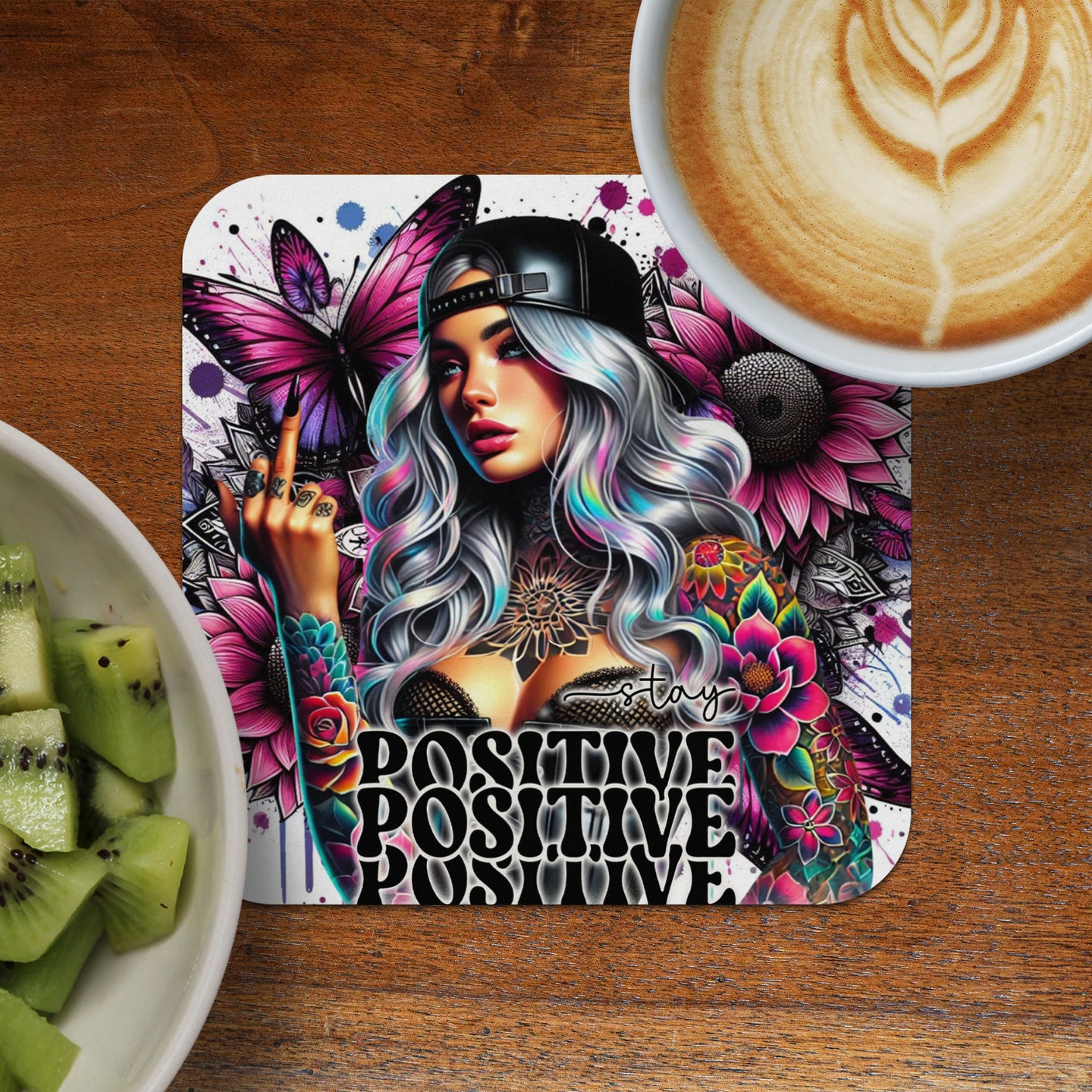 Tattooed woman with colorful hair and butterflies on a coaster, text "STAY POSITIVE".