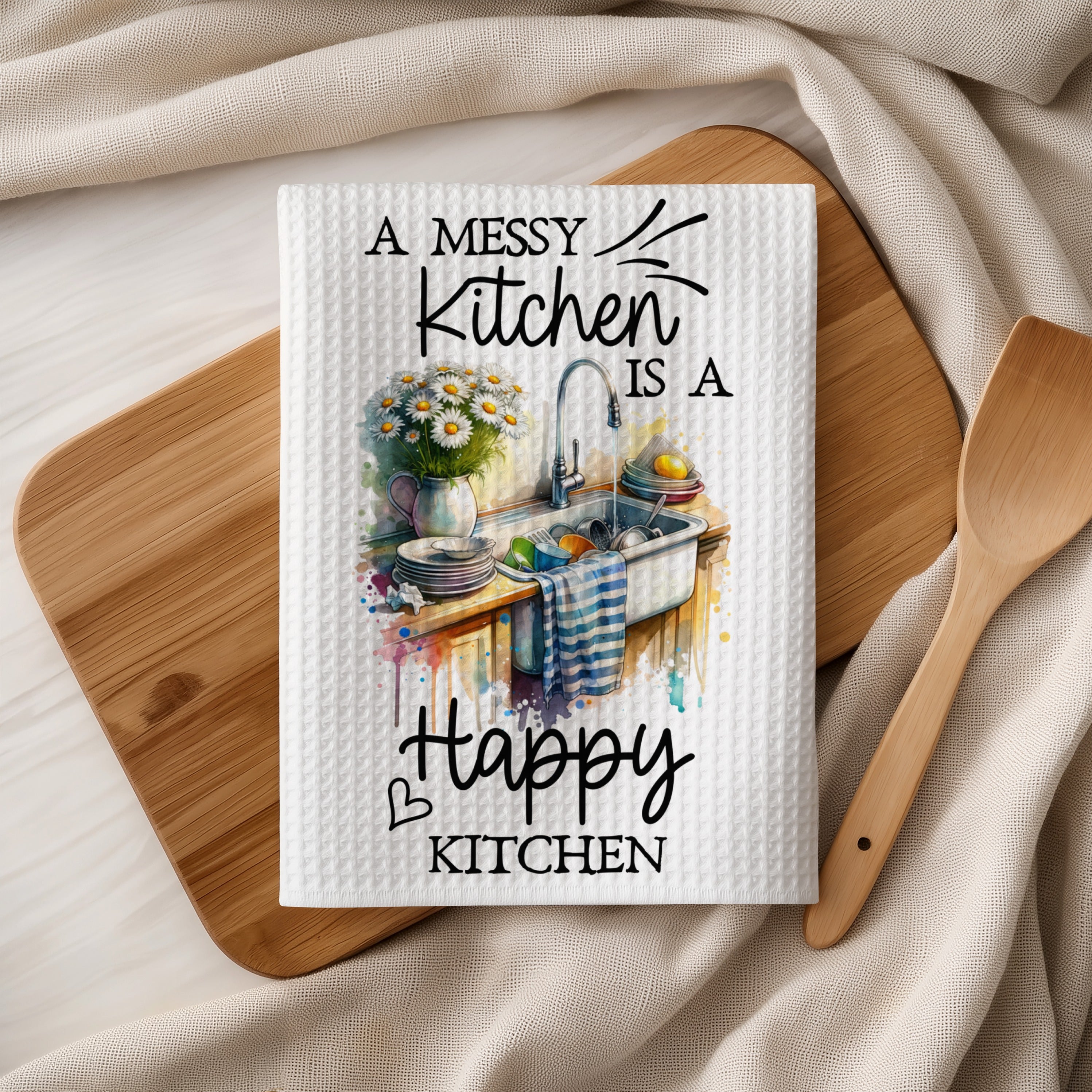 Kitchen towel with a watercolor illustration of a sink and the text "A messy kitchen is a happy kitchen."