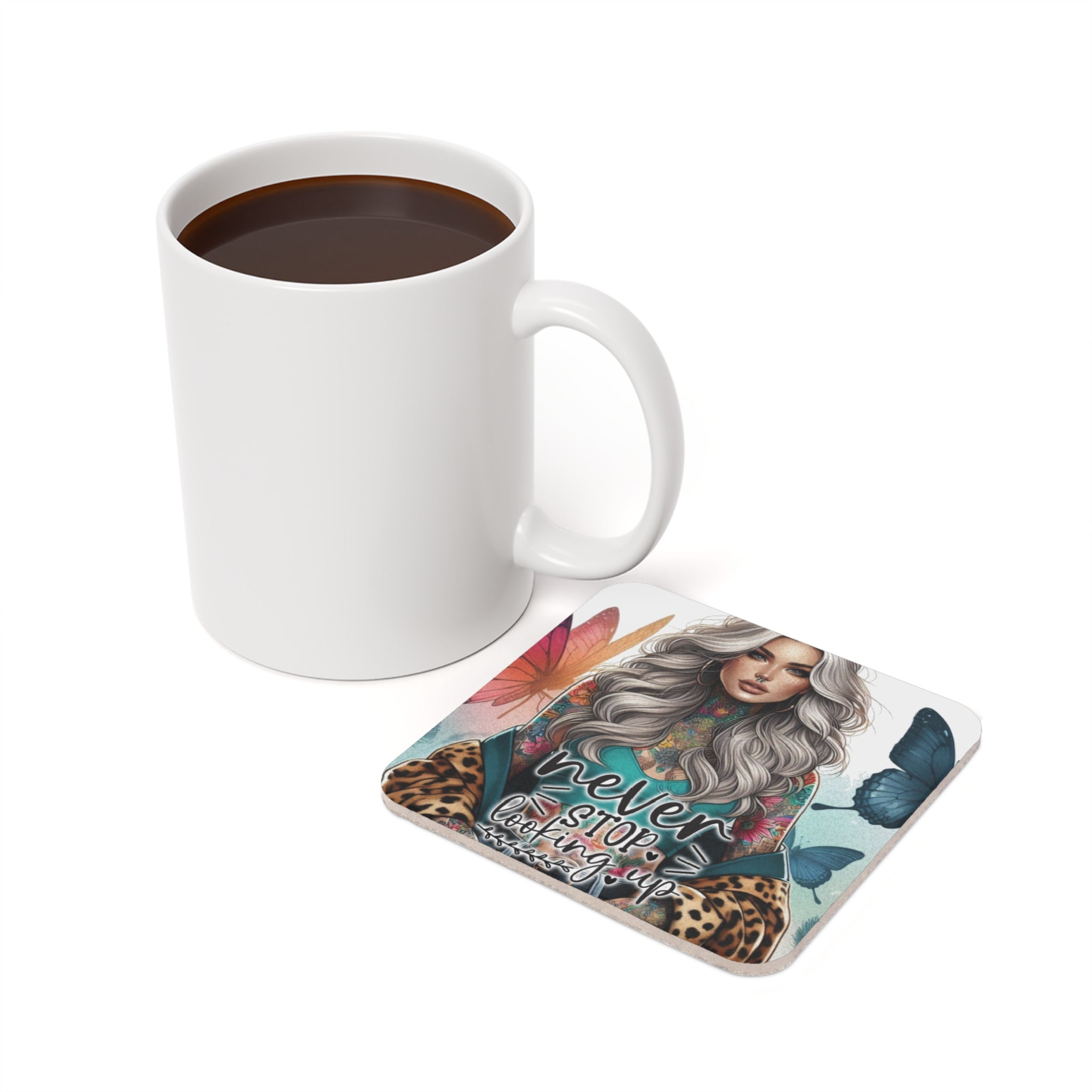 White mug with coffee next to a coaster with a woman and butterflies, "never stop looking up".