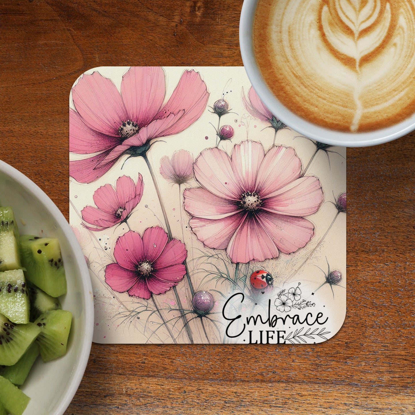 Pink cosmos flowers and a ladybug on a coaster with "Embrace Life" text.