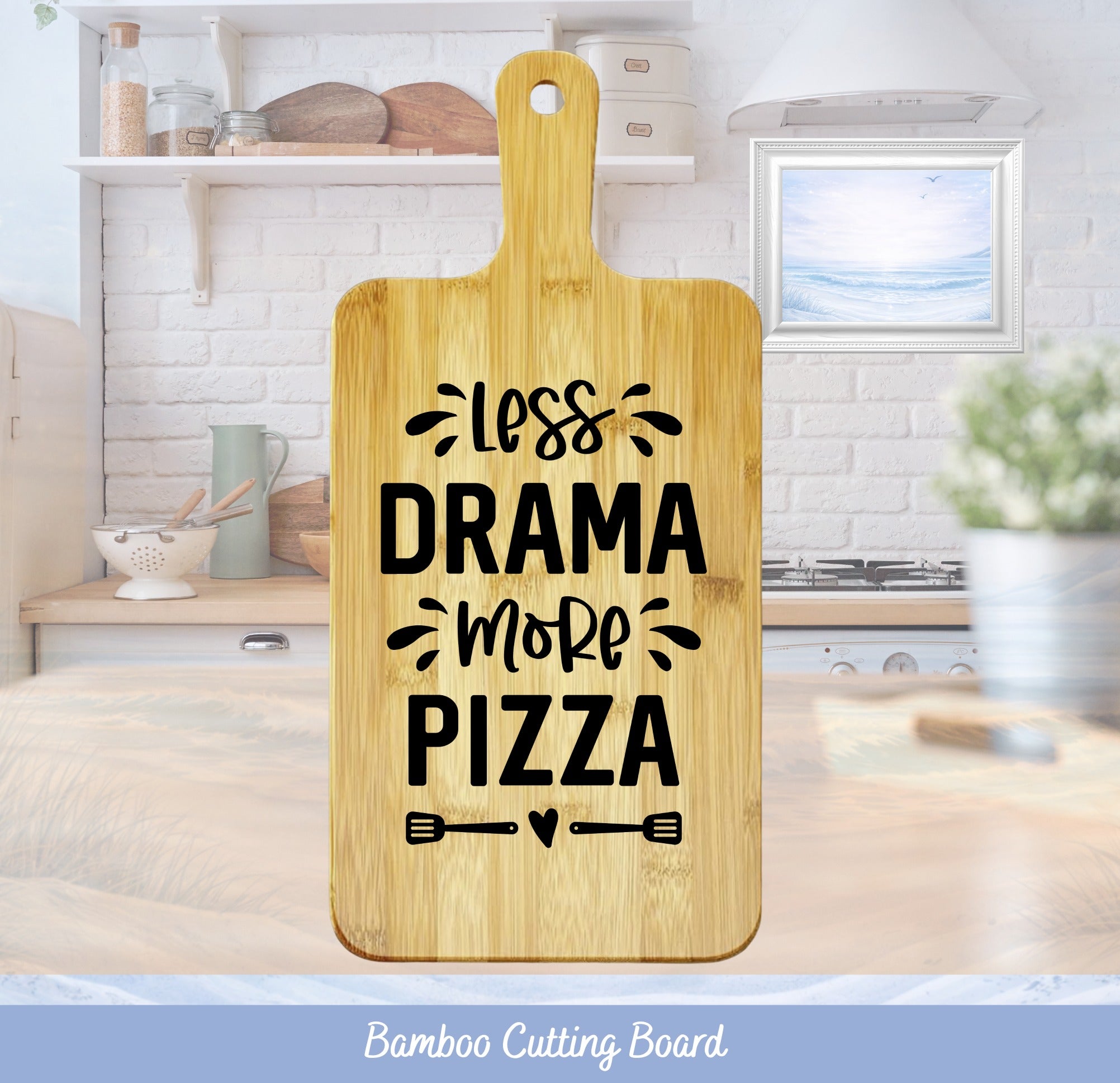 Bamboo cutting board with "less drama more pizza" text and kitchen background.