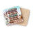 Stack of vintage books with feathers, jar, and a drink next to a coaster.