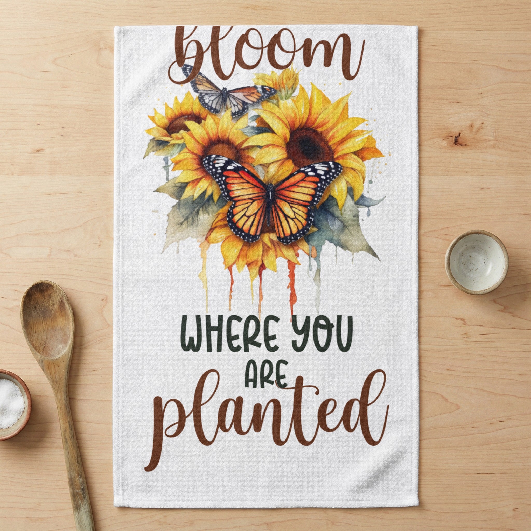 Sunflowers and butterflies on a kitchen towel with "Bloom where you planted" text.