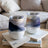 Two insulated tumblers with mountain landscape designs rest on books.