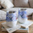 Two insulated tumblers with hummingbirds and floral patterns, resting on books.