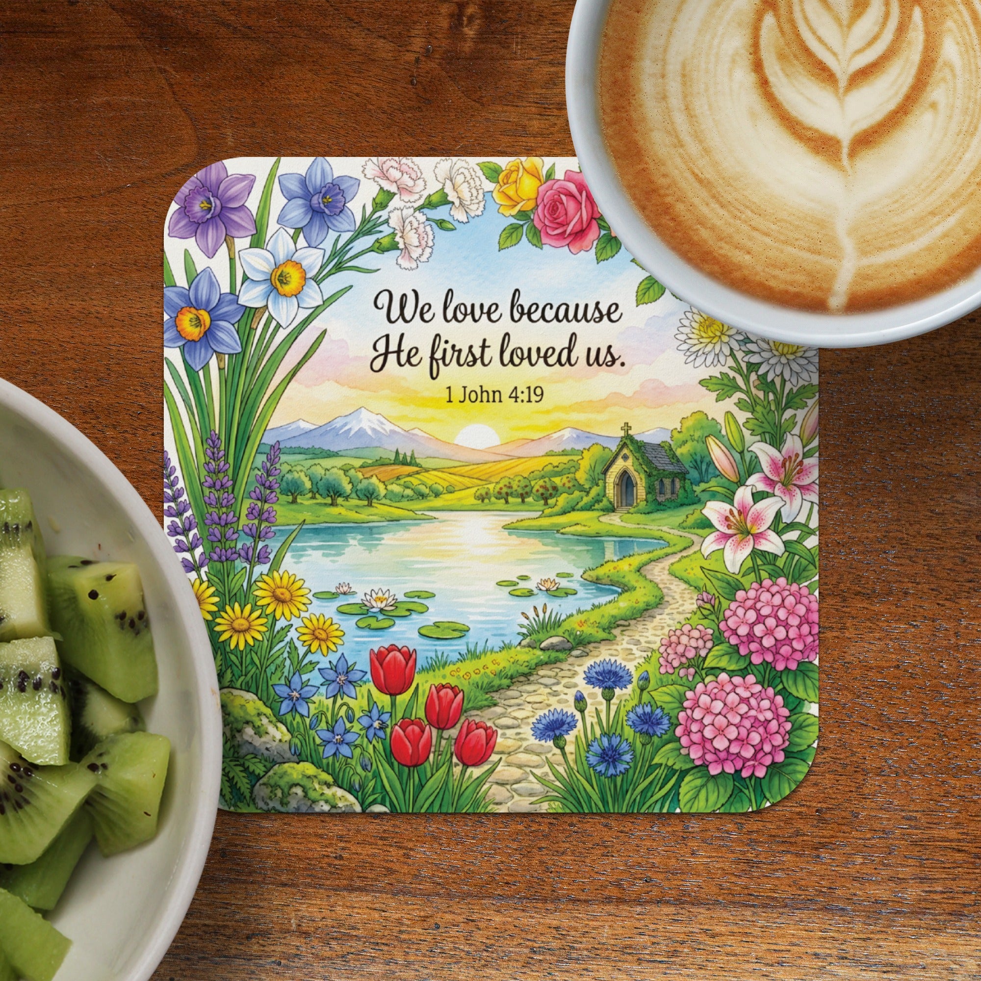 Floral landscape coaster with "We love because he first loved us." scripture.